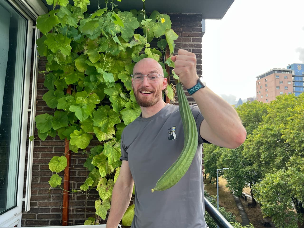 Me smiling on the balcony, holding a very long green vegetable